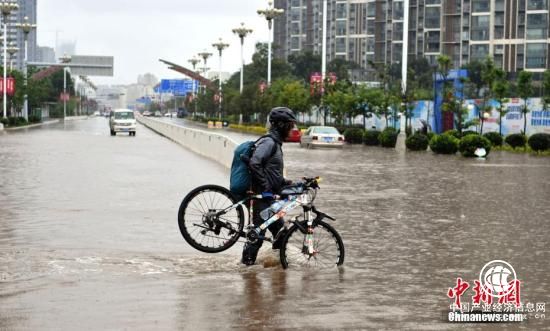 7月22日，民眾抬著自行車從積水路上走過。當(dāng)日，昆明持續(xù)降雨，城區(qū)多處路段積水。昆明市氣象臺發(fā)布暴雨藍(lán)色預(yù)警，未來12小時昆明市區(qū)及周邊多地區(qū)將持續(xù)降雨。 <a target=