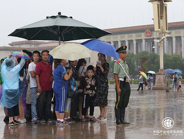 天安門(mén)廣場(chǎng)一執(zhí)勤武警將崗傘讓給群眾避雨，自己冒雨站崗